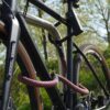 Fiets vastgemaakt aan het achterwiel, voorwiel en fietsframe met D-slot U-slot en eyelet textieltouw in chateau red op de fietsstandaard