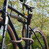 Fiets vastgemaakt aan het achterwiel, voorwiel en fietsframe met D-slot U-slot en eyelet textieltouw in wild hemp op de fietsstandaard