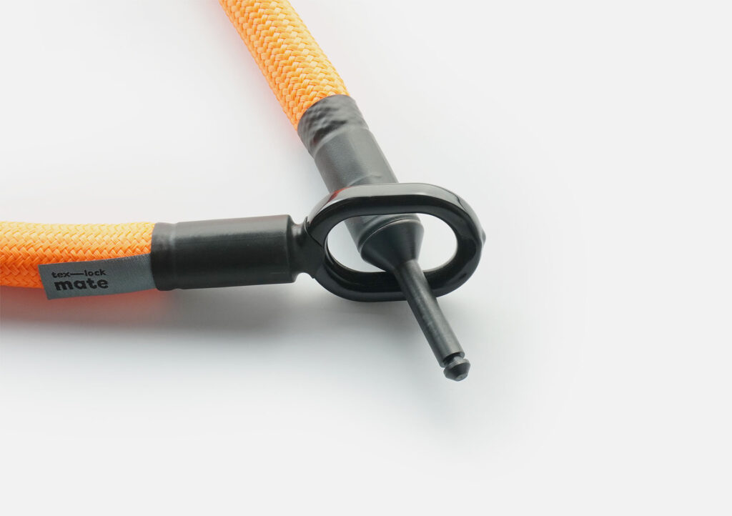 Schließbolzen des tex–lock mate in acid orange durch Metallöse