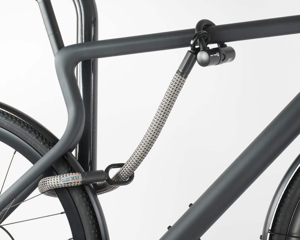 Rear wheel and top tube of the bike connected to the bike stand with U-lock and textile extension in gray-black