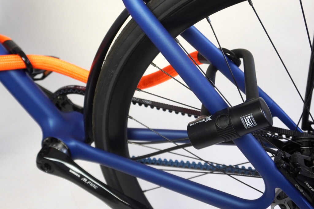 Tex-lock eyelet mit X-Lock und Loop-Through um blauen Fahrradrahmen und Hinterrad