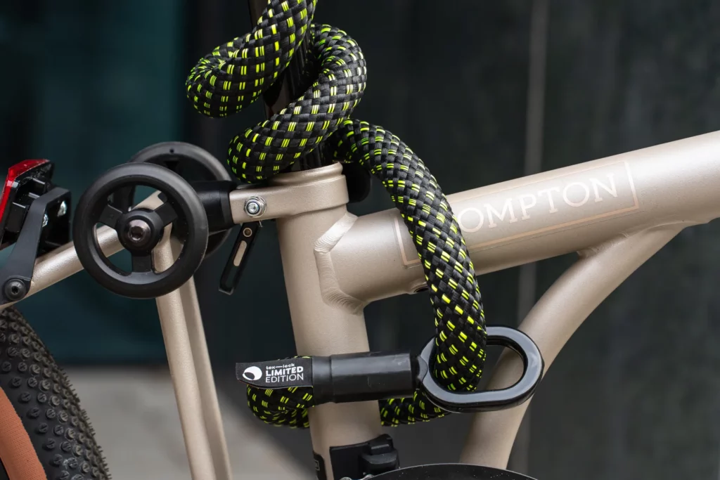Zwart fietsslot met neonkleuren omsluit Brompton vouwfiets
